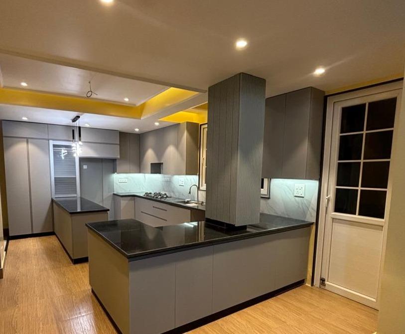 Grey kitchen with black granite counter and fluted island panel