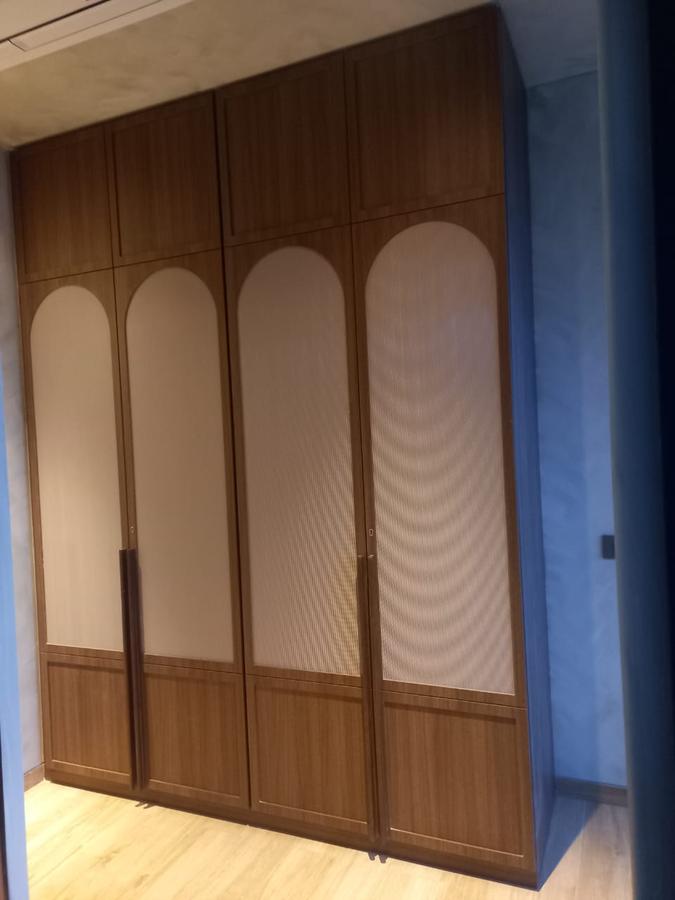 Arched wardrobe in warm walnut finish with fabric-inset panels