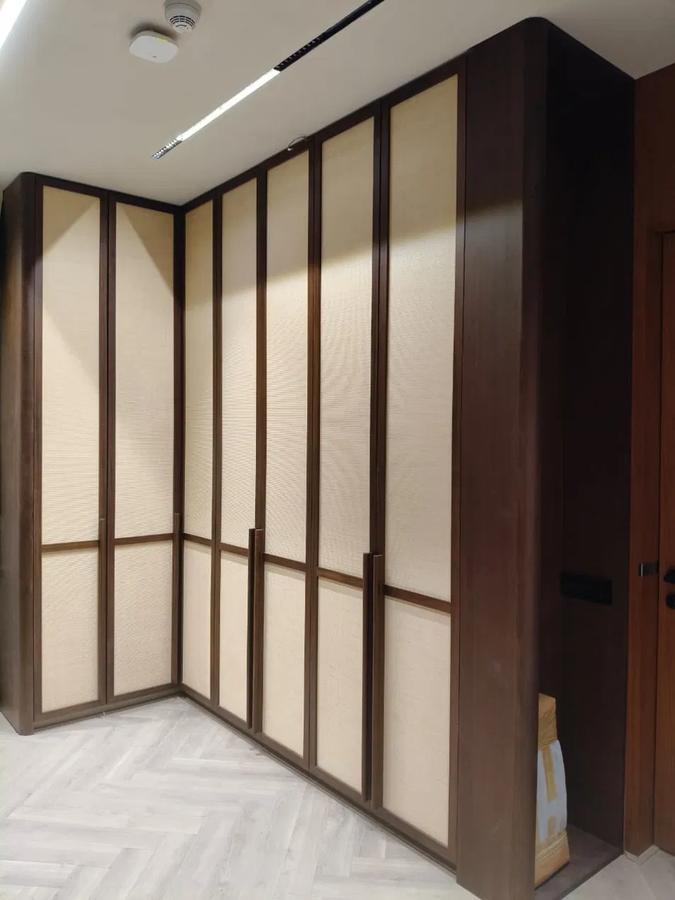 Walnut corner wardrobe with fabric-inset panels, herringbone floor