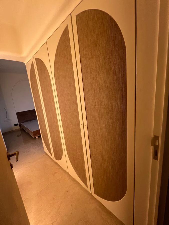 Beige wardrobe with oval wood-panel door inlays